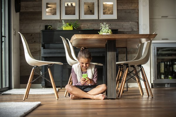 Girl sitting on floor texting on cell phone