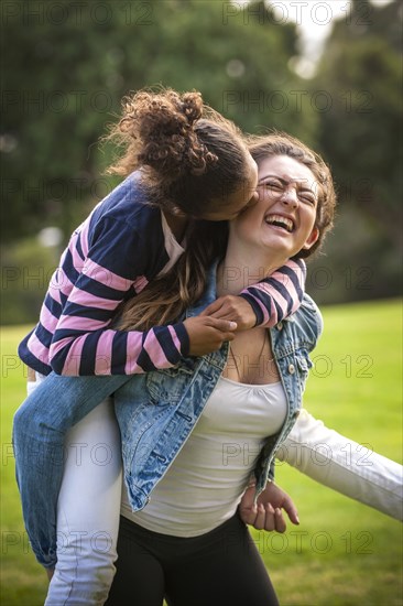 Portrait of laughing girl carrying sister piggyback