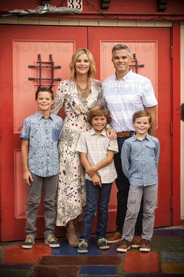 Portrait of smiling family posing near red doors