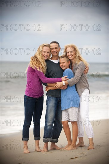 Portrait of smiling family hugging on beach