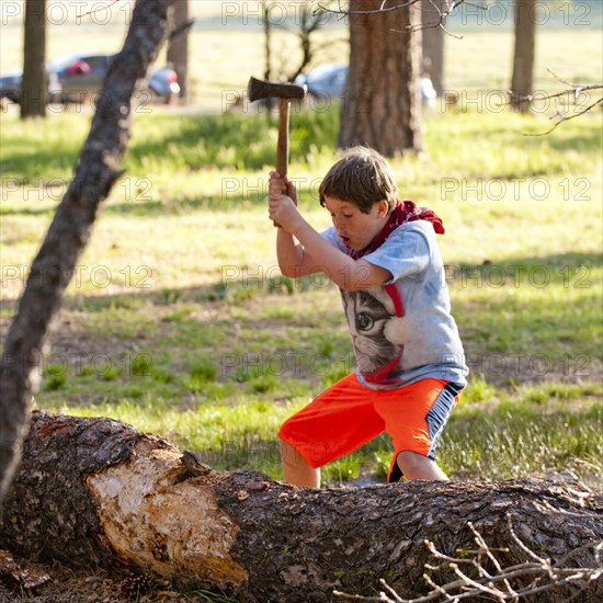 Caucasian boy chopping log with axe