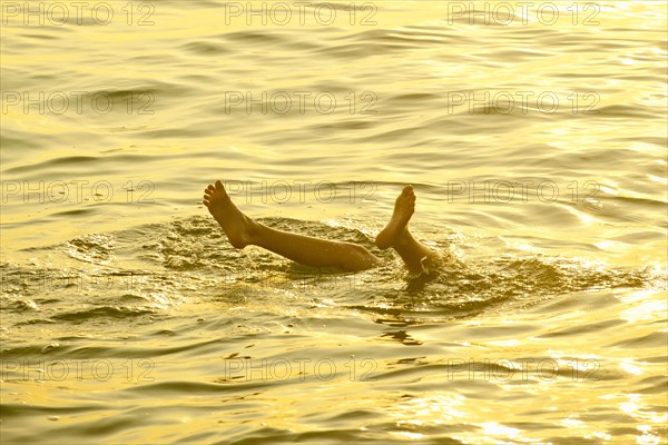 Feet of Caucasian boy sticking out of water