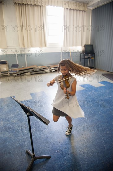 Caucasian girl practicing violin and dancing