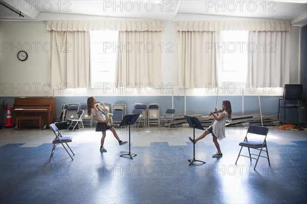 Caucasian girls practicing violins and dancing
