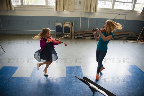 Caucasian girls practicing violins and dancing