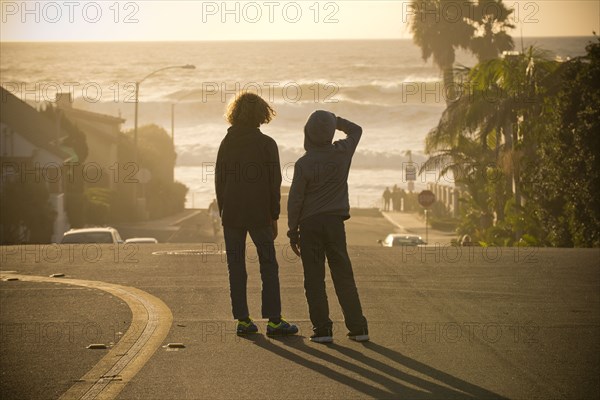 Boys standing in street admiring ocean waves