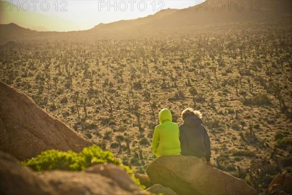 Boys sitting on rock admiring desert landscape