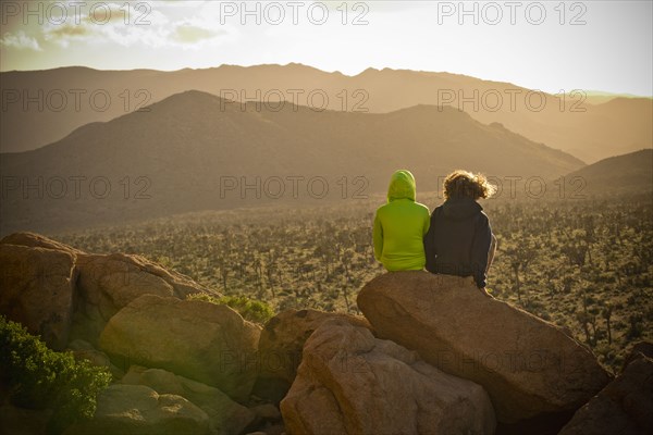 Boys sitting on rock admiring desert landscape