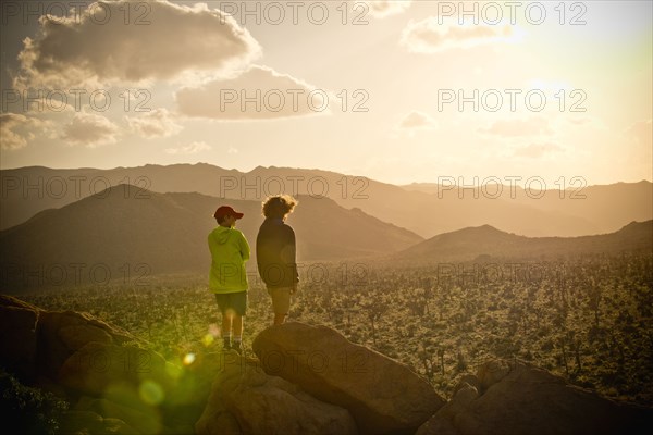 Boys standing on rock admiring desert landscape