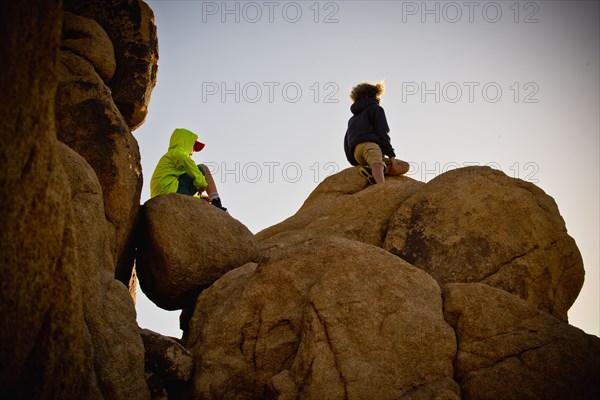 Boys sitting on rocks under blue sky