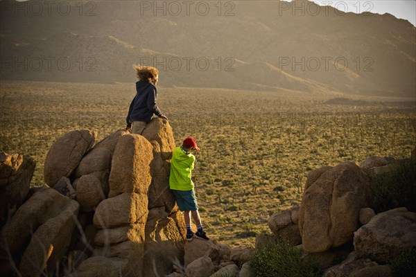 Boys standing on rocks admiring desert landscape