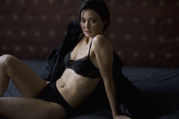 Serious Hispanic woman in lingerie with fur coat