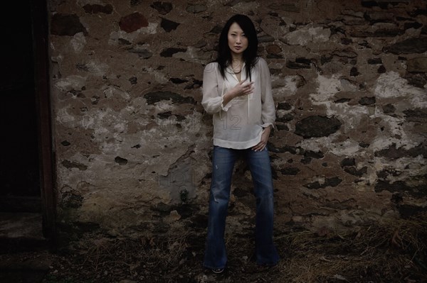 Serious Asian woman leaning against wall