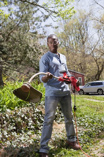 Black man holding weed trimmer