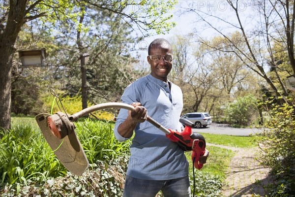 Black man holding weed trimmer