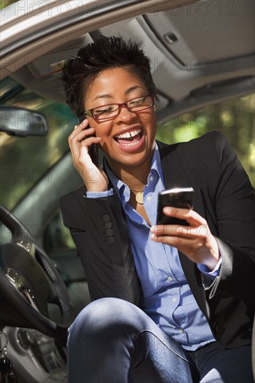 Black woman in vehicle using two cell phones