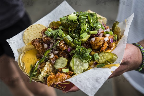 Hand holding loaded nachos