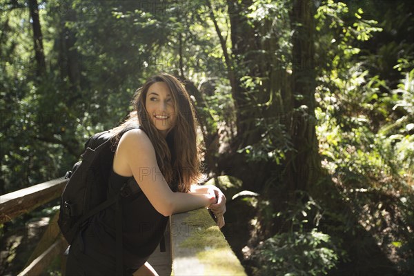 Caucasian woman standing on wooden bridge in forest