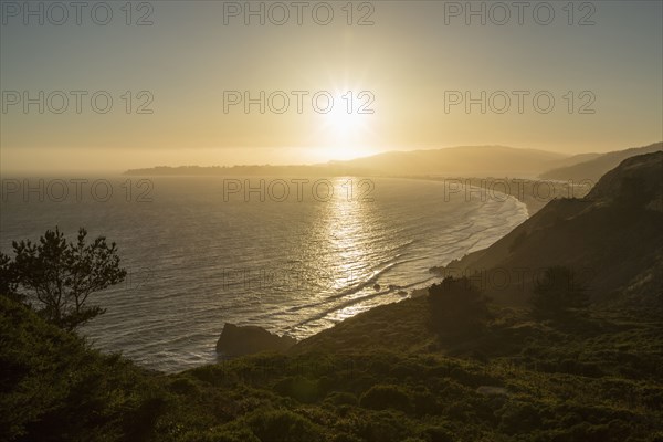 Sun setting over coastal landscape