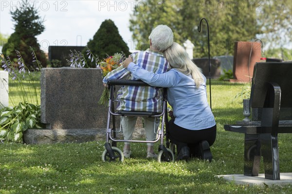 Caucasian mother and daughter visiting grave in cemetery