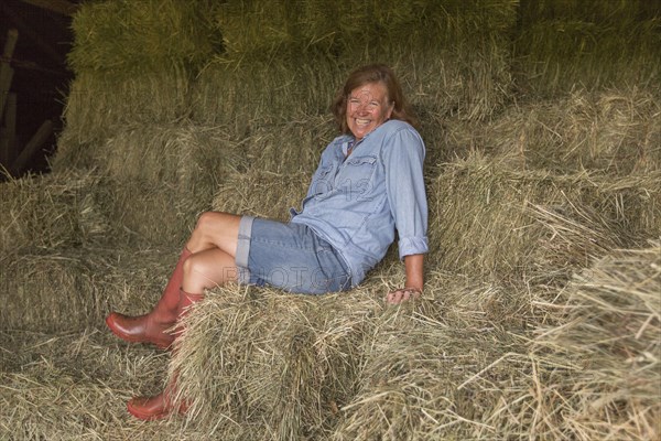 Older Caucasian woman sitting on hay bales