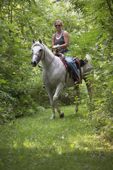 Caucasian woman riding horse in rural field