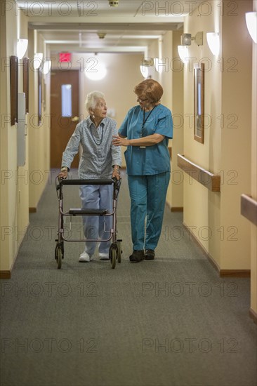 Older Caucasian woman walking with nurse in nursing home