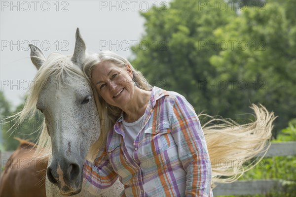 Older Caucasian woman petting horse outdoors