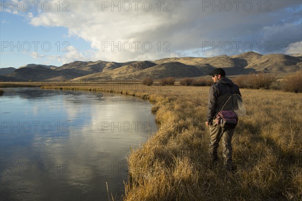 Man carrying fishing supplies near river