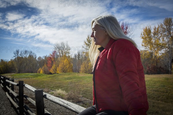 Older Caucasian woman sitting on wooden fence