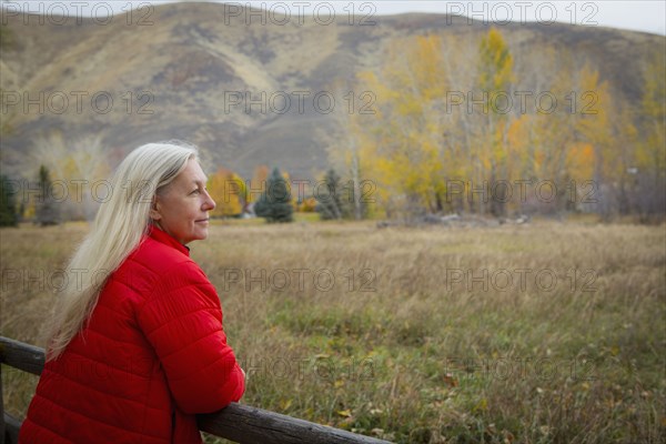 Older Caucasian woman leaning on wooden fence