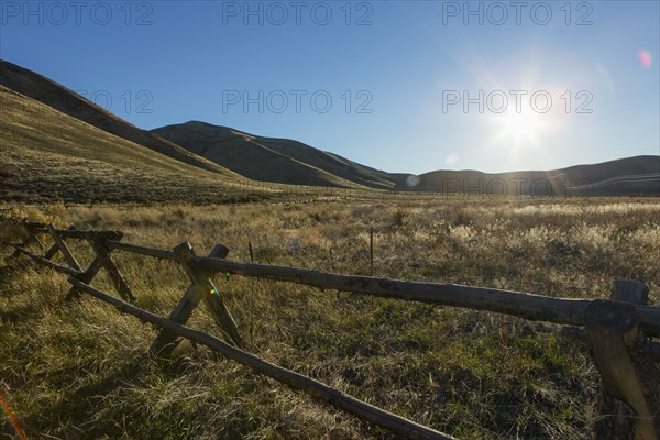 Wooden fence and rural field under blue sky