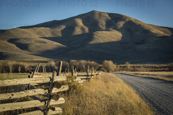 Wooden fence and rural field near mountain