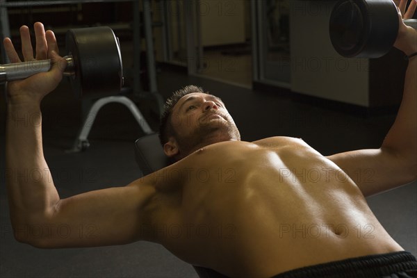 Caucasian athlete lifting weights in gymnasium