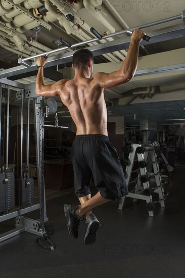 Caucasian athlete doing pull-ups in gymnasium