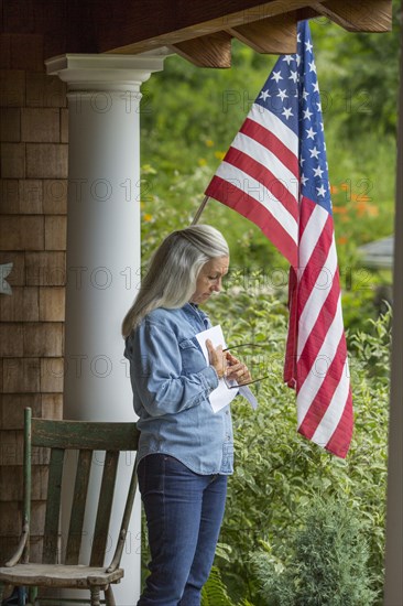 Caucasian woman reading letter on porch