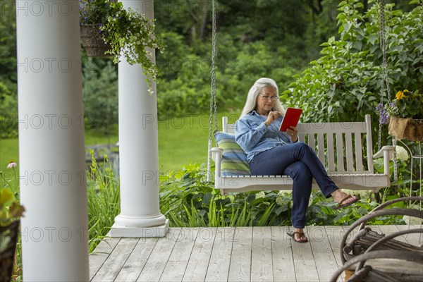 Caucasian woman using digital tablet on porch swing