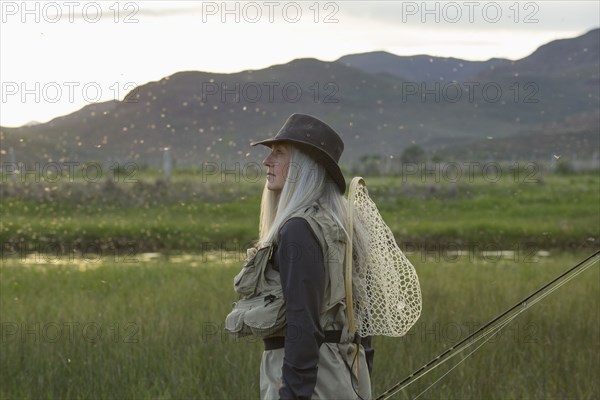 Caucasian woman wearing fishing gear in remote lake