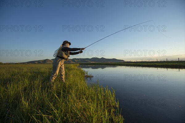 Caucasian woman casting fishing line in remote lake