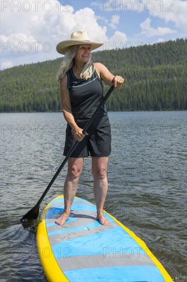 Caucasian woman standing on paddle board in lake