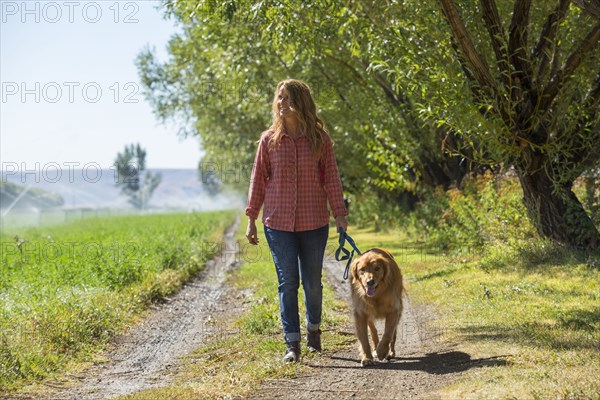 Caucasian woman walking dog on dirt path