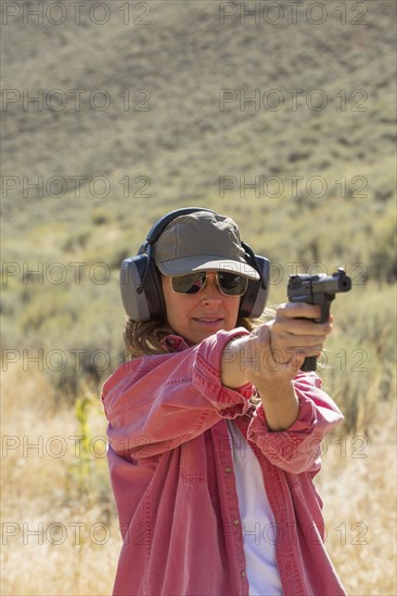 Caucasian woman aiming gun outdoors