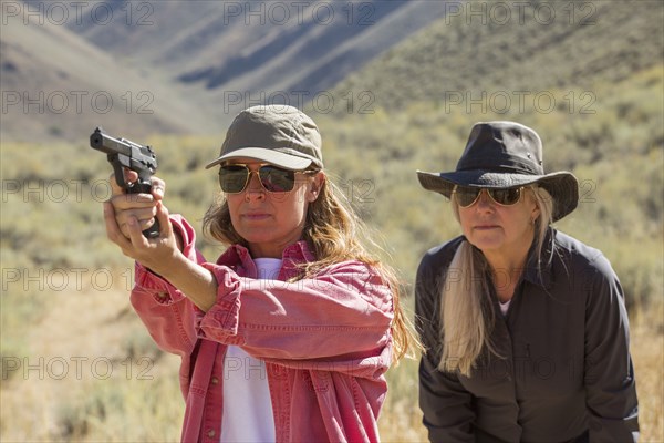 Caucasian women aiming gun outdoors