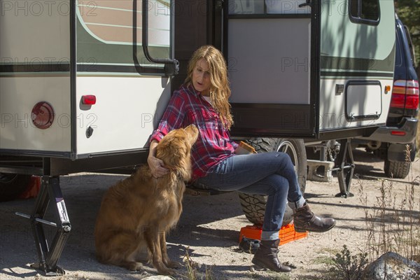 Caucasian woman petting dog at trailer