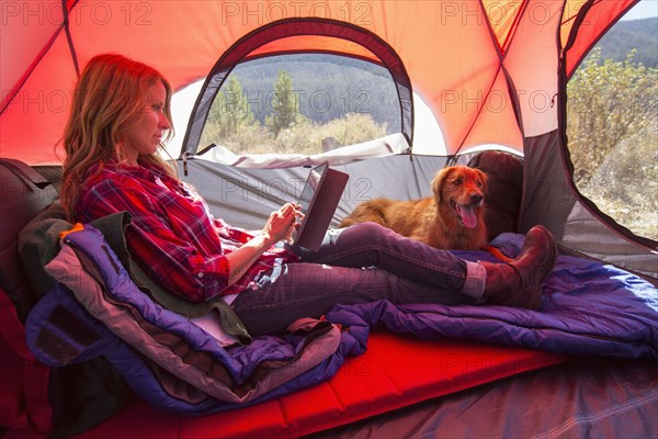 Caucasian woman using digital tablet in camping tent
