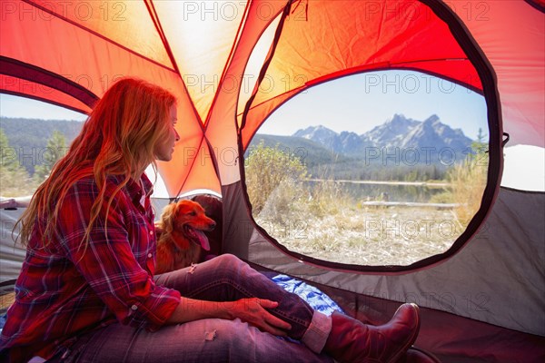 Caucasian woman and dog in camping tent