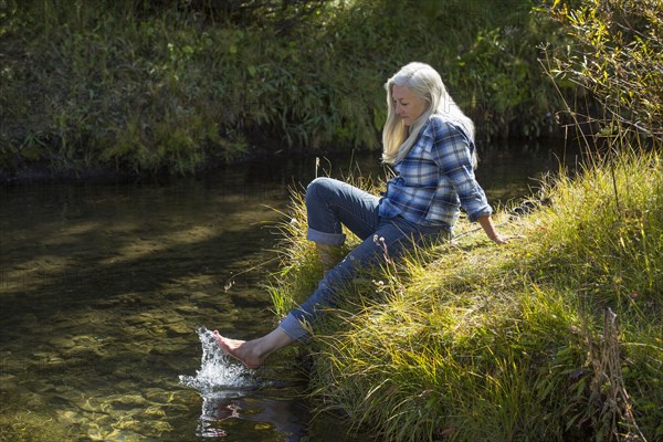 Caucasian woman splashing feet in river