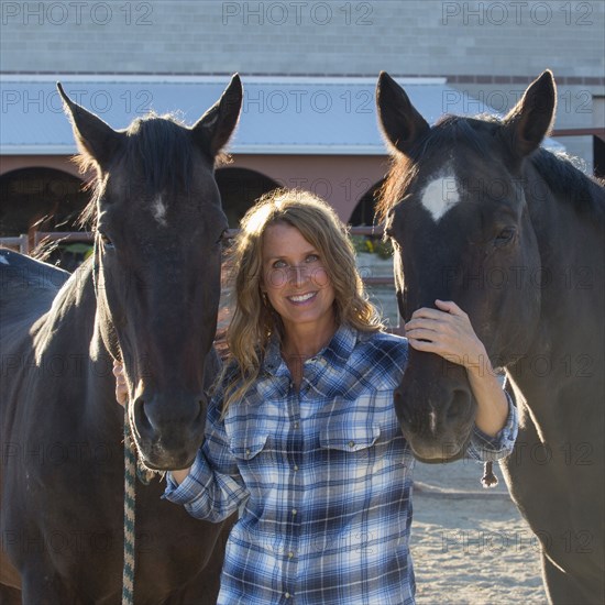 Caucasian rancher smiling with horses