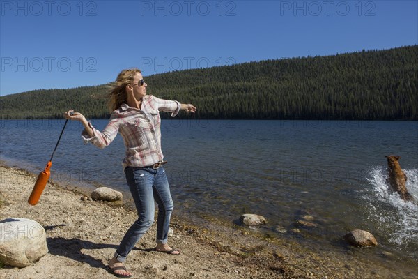 Caucasian woman playing with dog in river