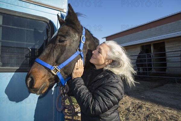 Caucasian woman petting horse on ranch
